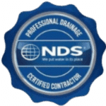 Blue badge with "Professional Drainage Certified Contractor" around the edge and "NDS - We put water in its place" with a globe logo in the center.